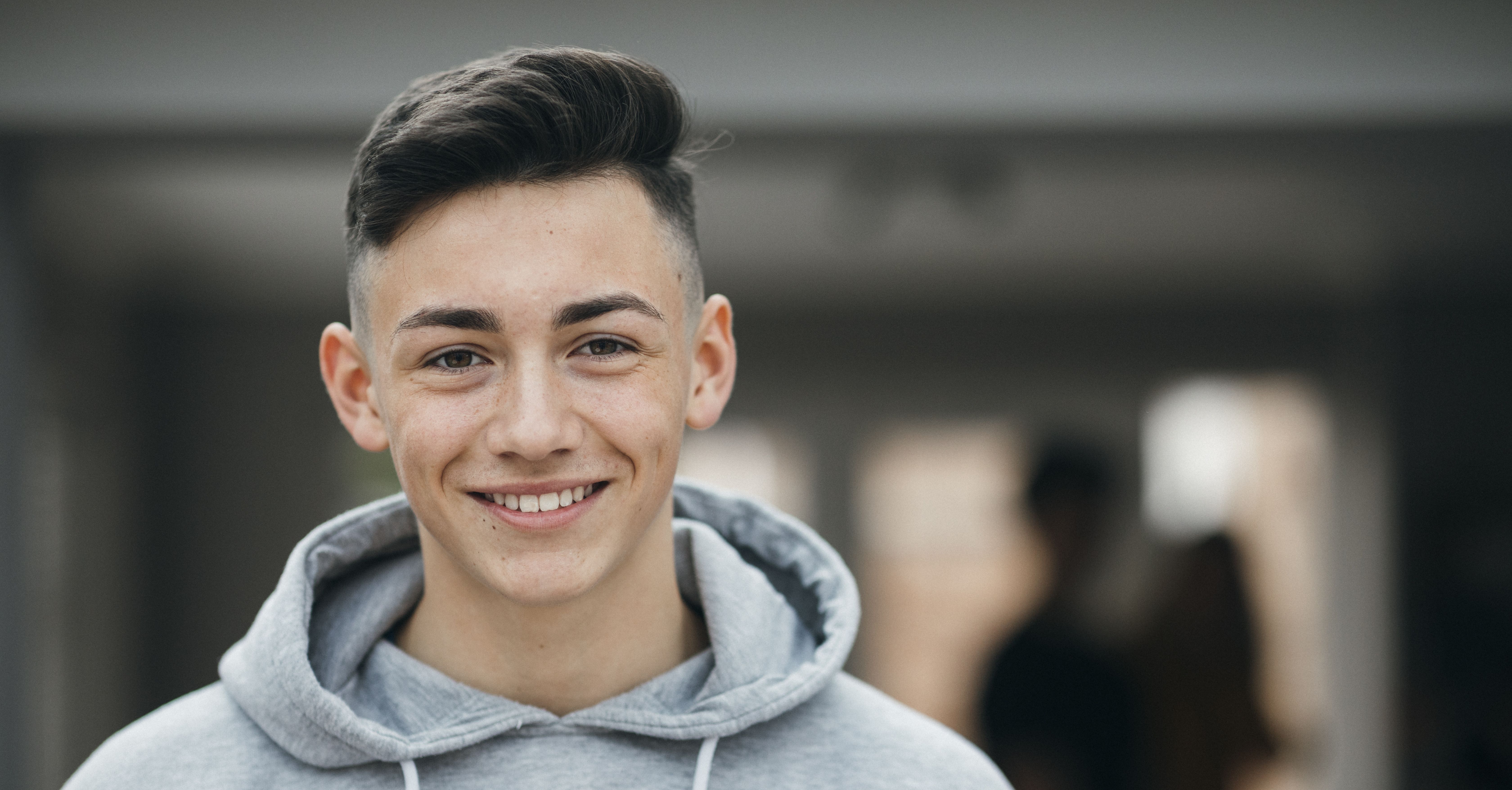 Lachender Lernender mit grauem Kaputzensweater