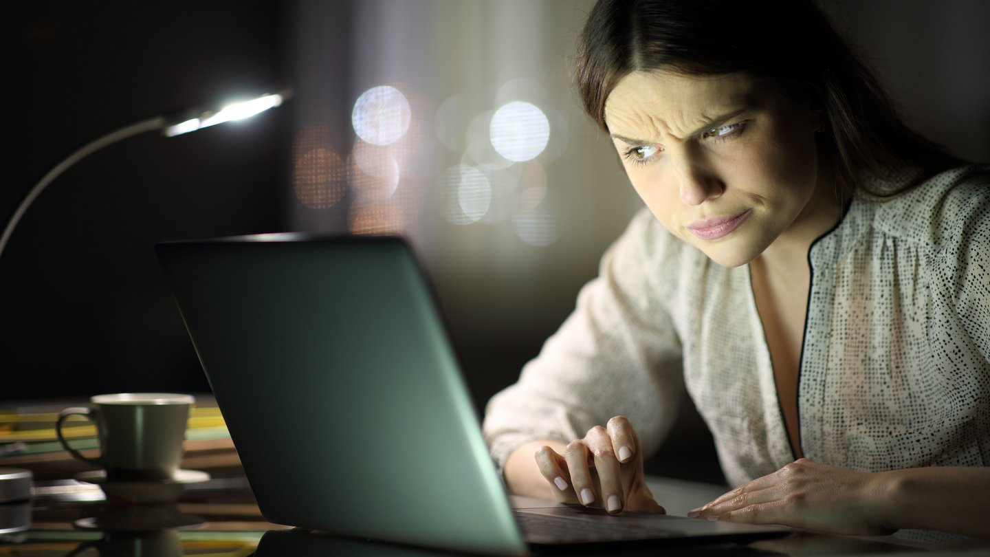 Frau überprüft verdächtige Phishing Nachrichten auf ihrem Laptop.