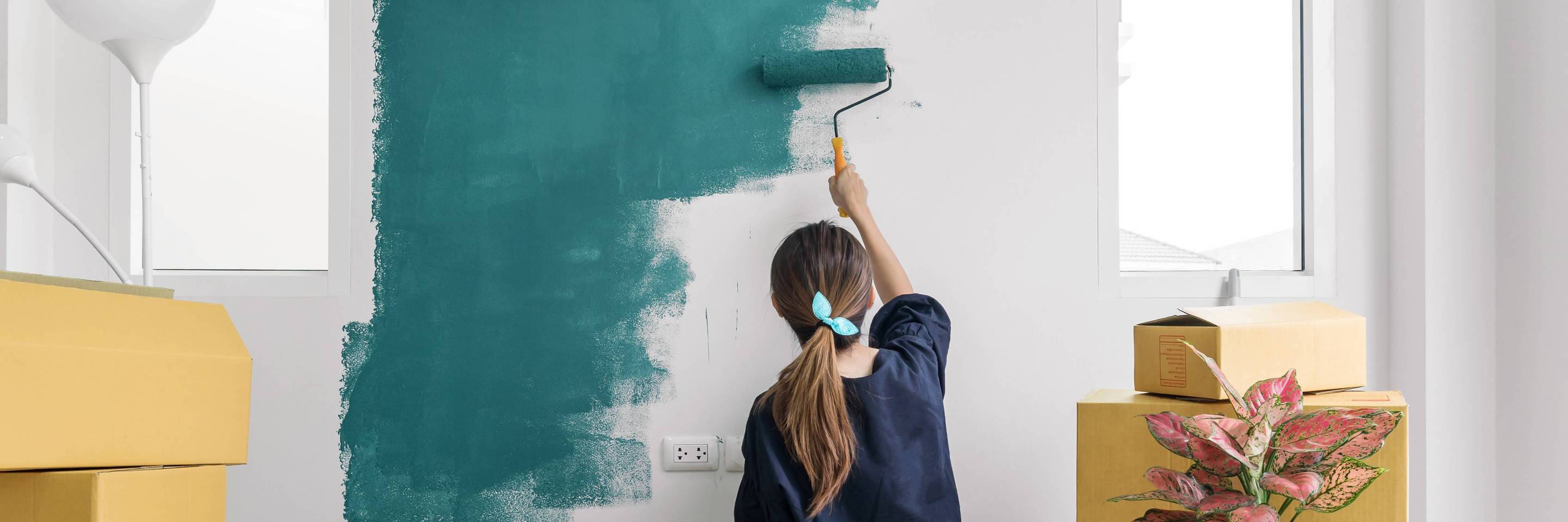 Frau beim Umzug streicht eine Wand in Green Farben