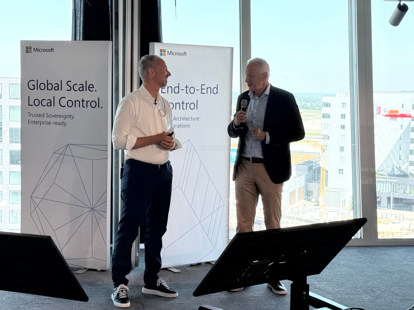 Chris Keller von Green (links) im Gespräch mit seinem Interviewpartner auf einer Microsoft-Veranstaltung vor Postern zur Cloud-Souveränität.