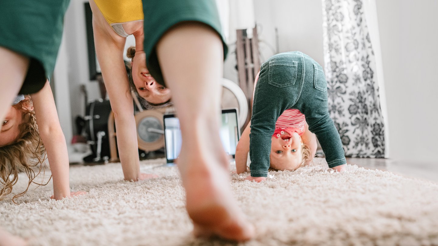 Une mère avec ses enfants fait du yoga à la maison.