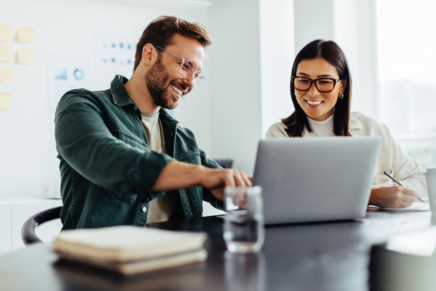 Mann und Frau besprechen etwas und zeigen dabei auf Laptop