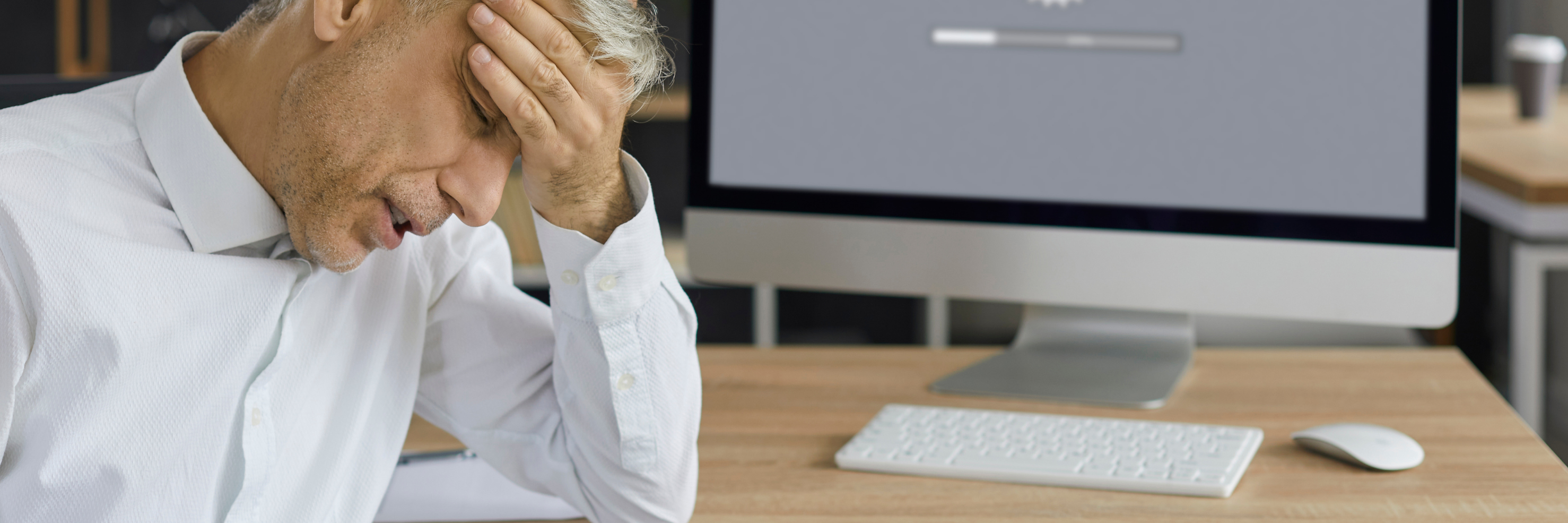 Mann im Büro mit Frustration vor einem Computer, der langsam lädt – Symbolbild für schlechte Website-Performance
