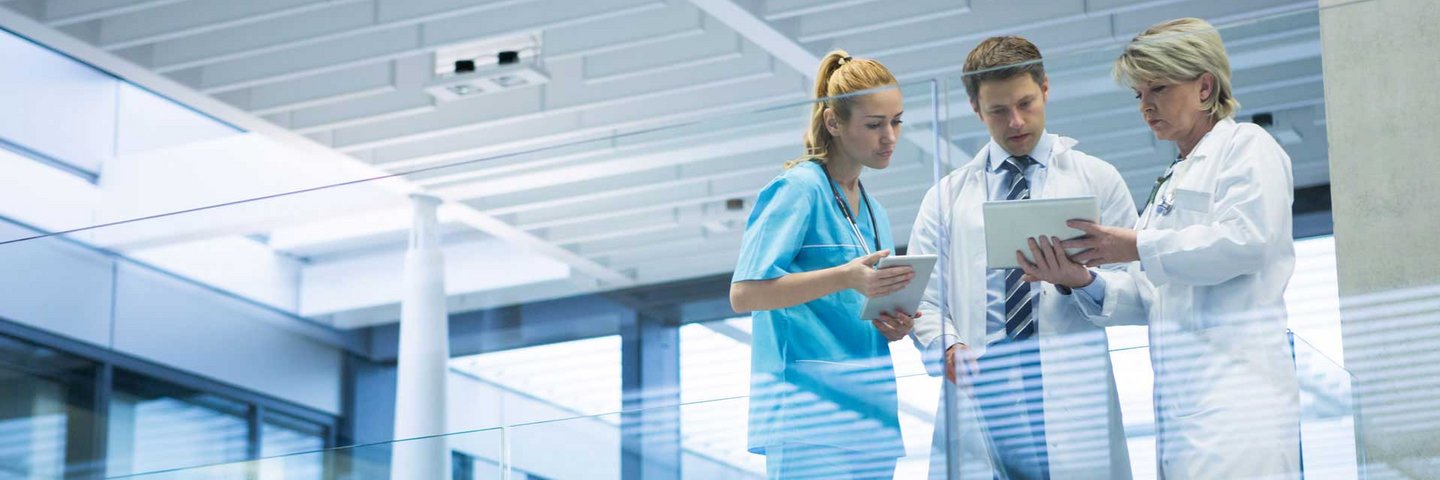 Three people in scrucs in discussion in a hospital