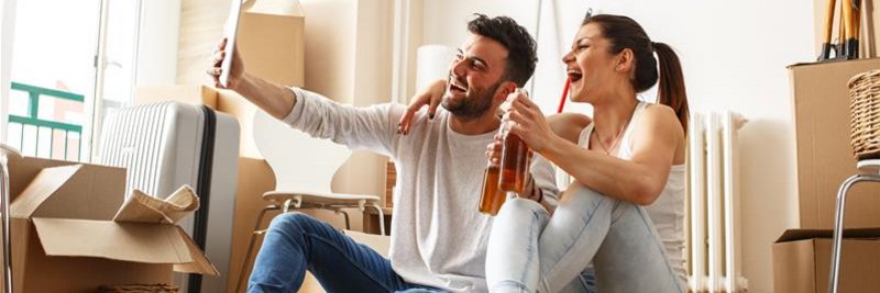 Paar beim Umzug, entspannt auf dem Boden sitzend und einem Drink in der Hand, umgeben von Kisten – symbolisch für den reibungslosen Umzug mit schnellem Internetanschluss.