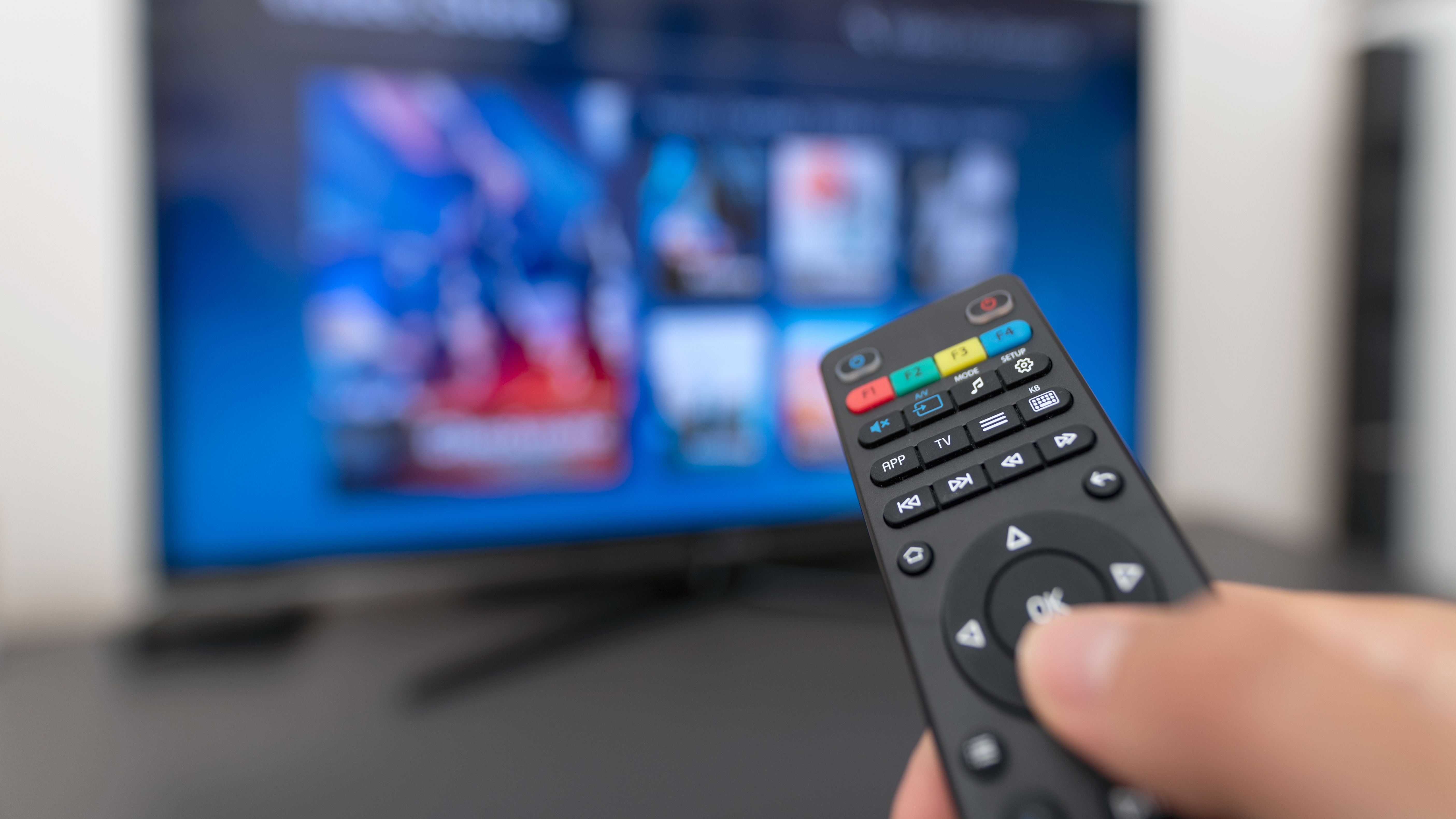 Eine Person bedient die Fernbedienung und schaut TV von Green