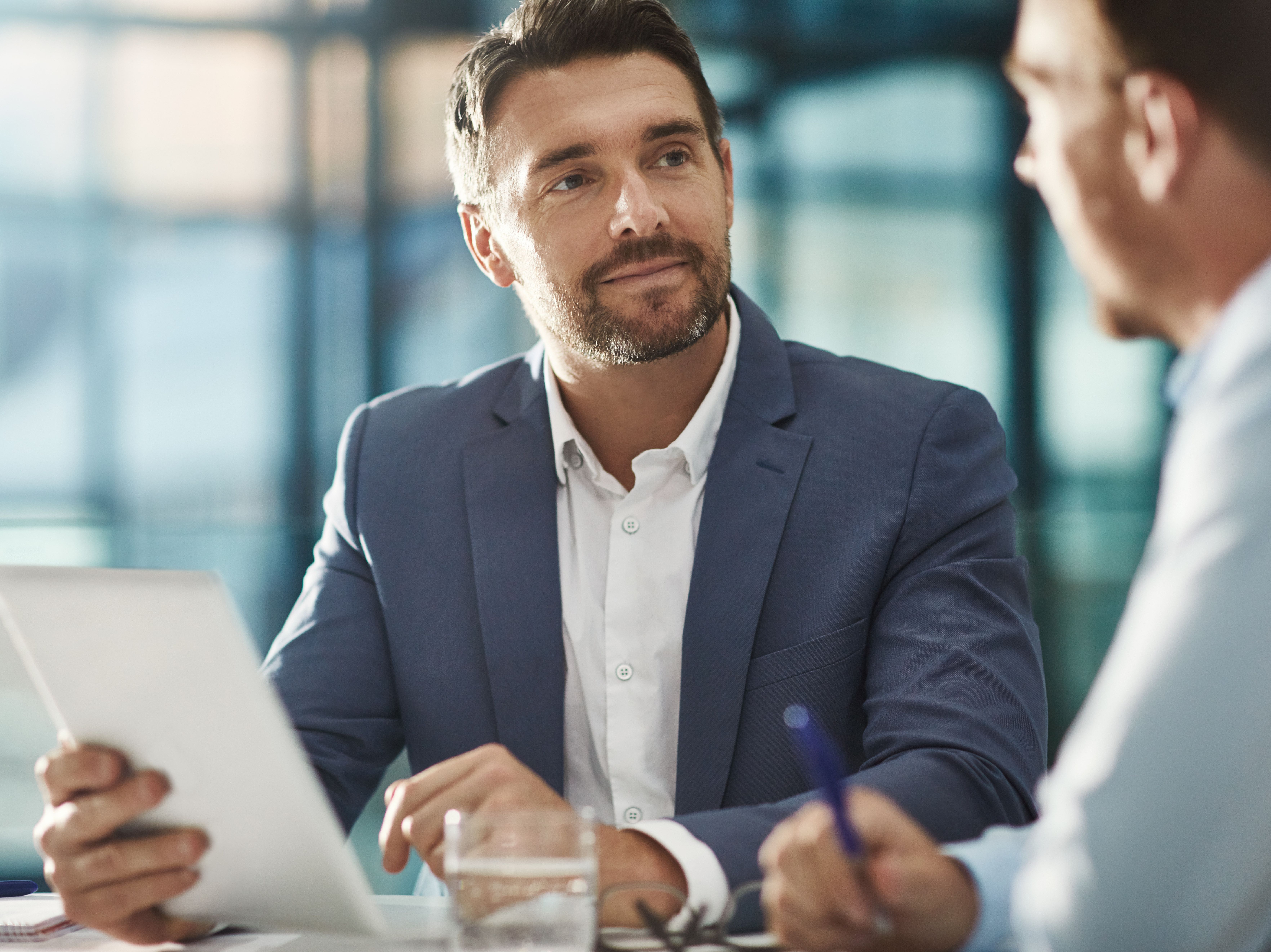 Man in a suit listens to another man while talking