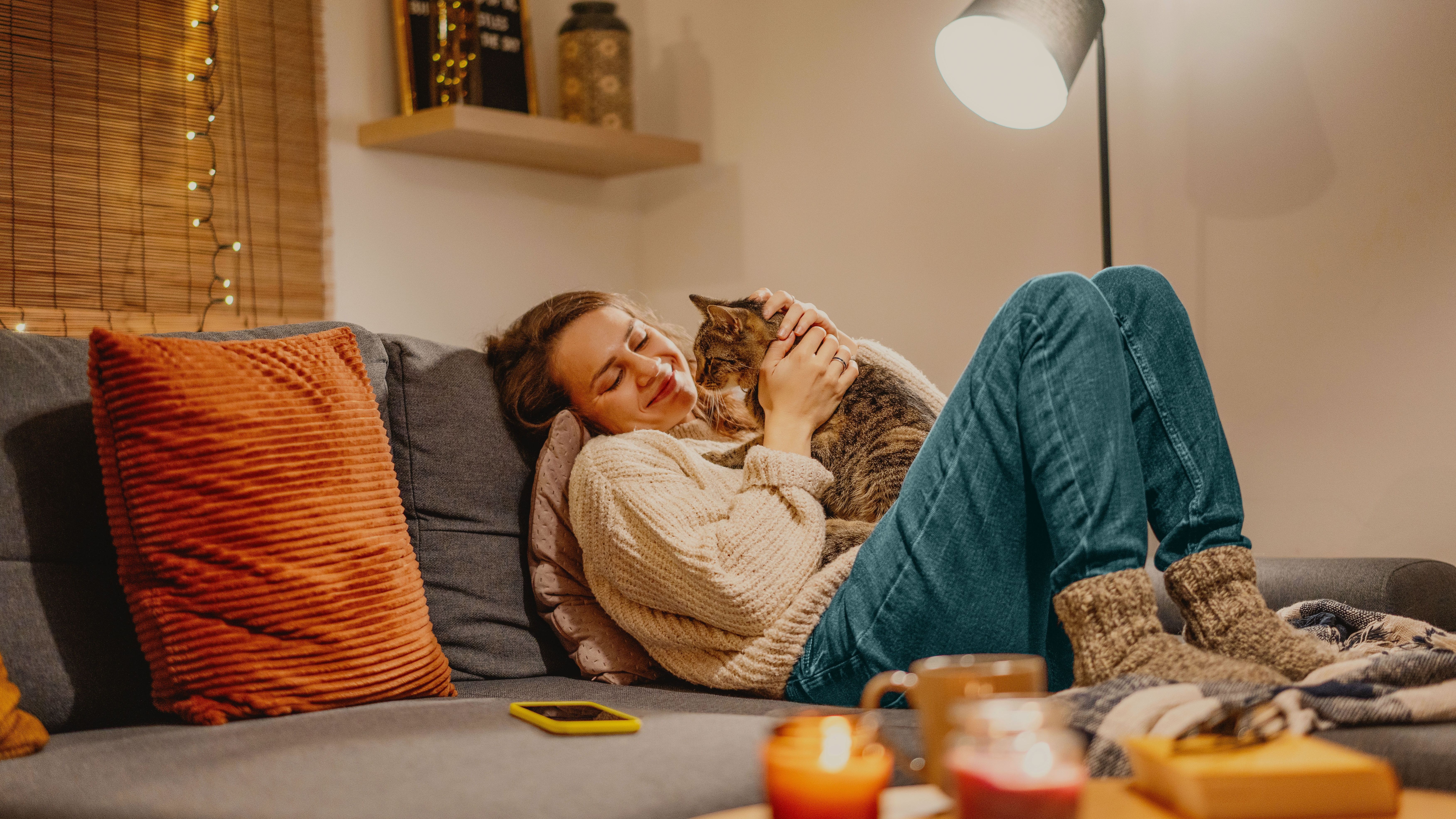 Young woman sitting comfortably on the sofa with her cat.