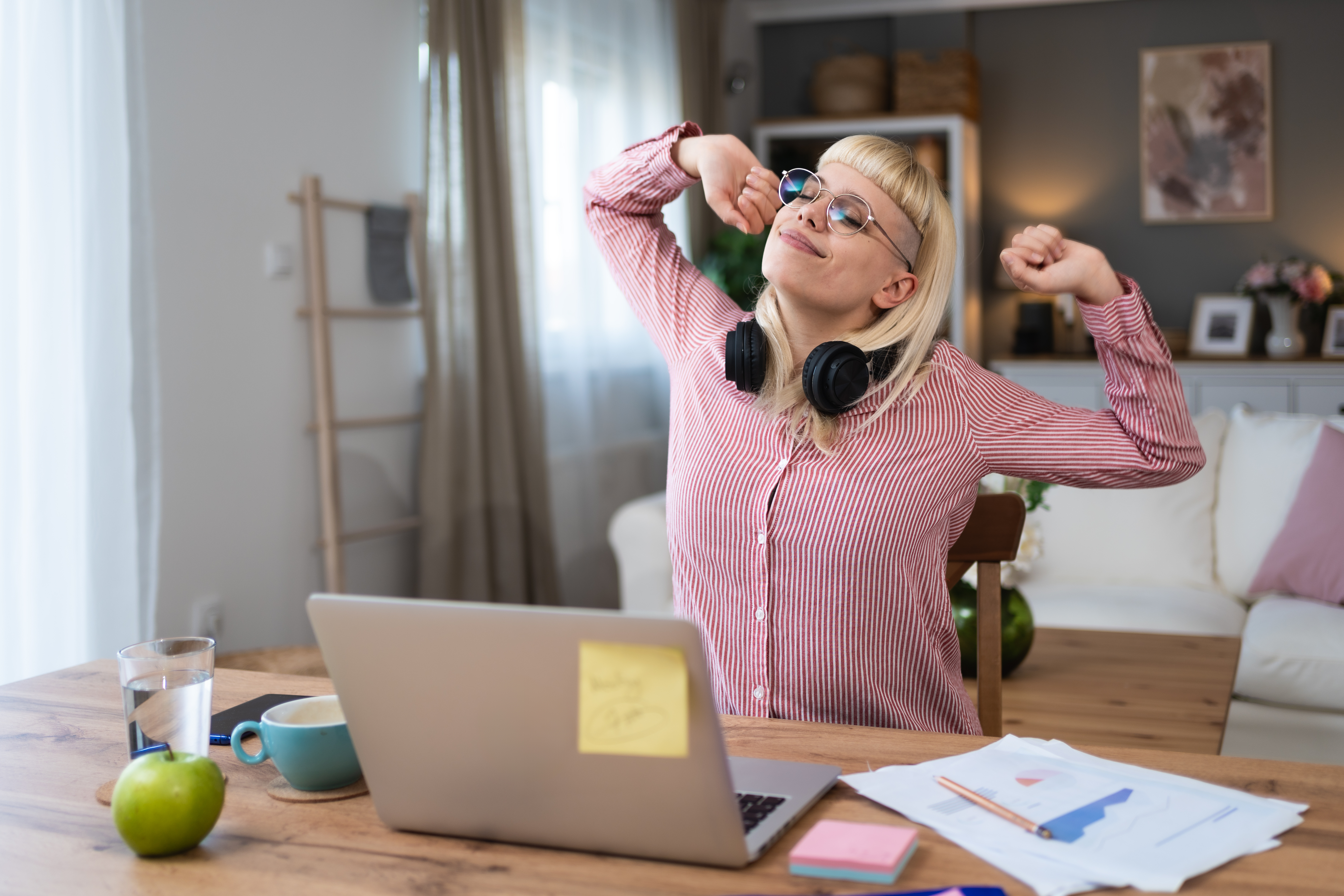 A woman at her desk in front of a laptop stretches and relaxes comfortably