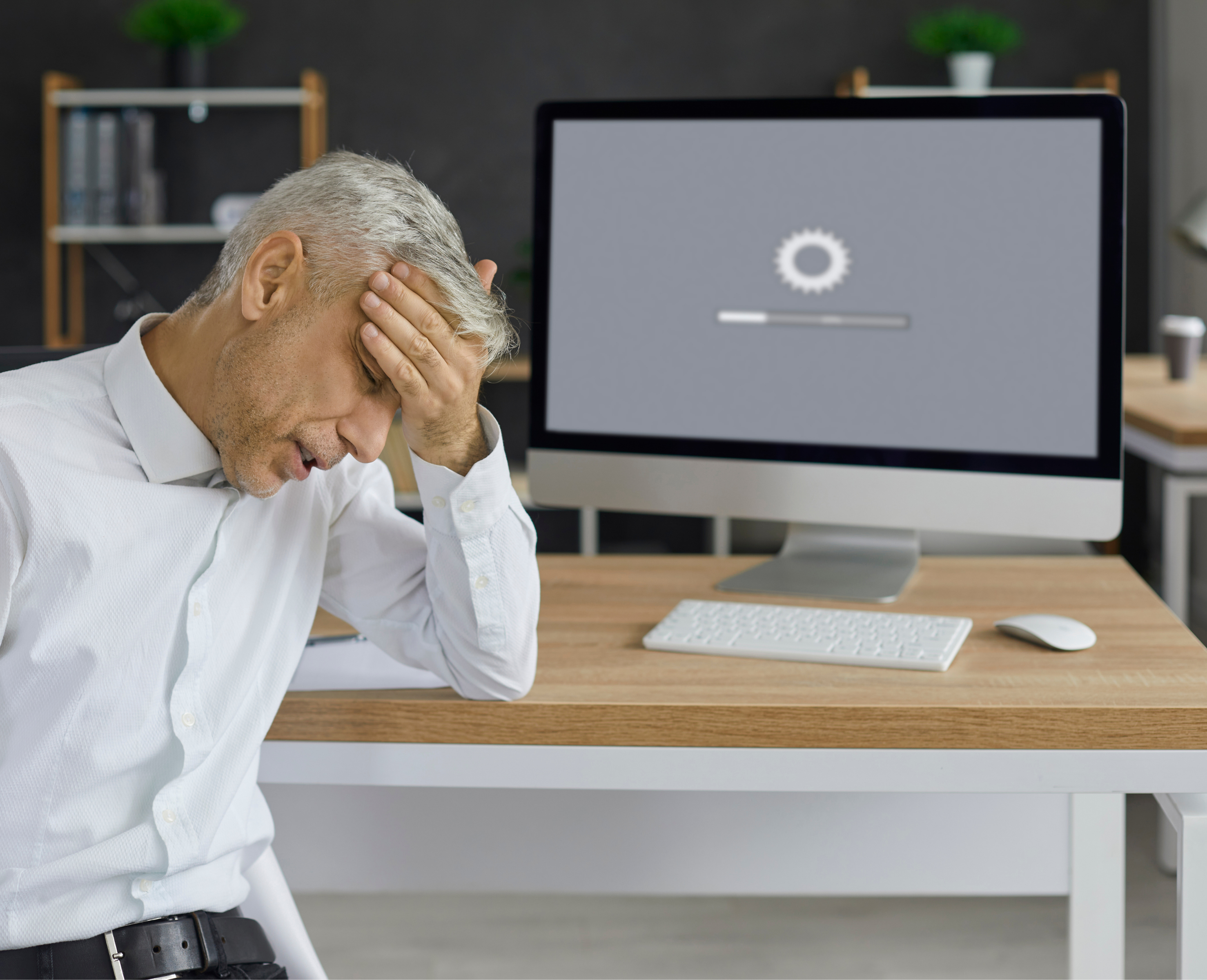 Frustrated man in an office sitting in front of a computer with a slow-loading screen – symbolic of poor website performance